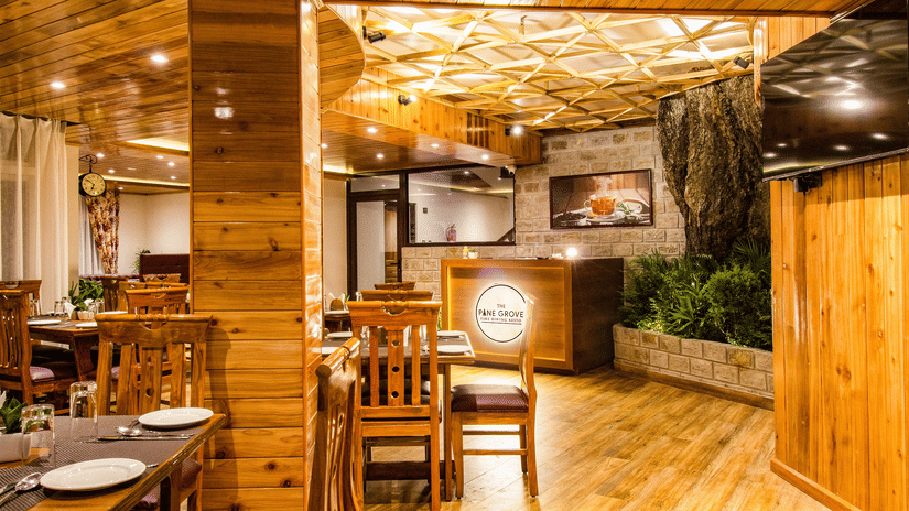 The Pine Grove Fine Dining Resto, the best restaurant in Darjeeling, featuring warm wooden interiors, cosy seating, ambient lighting, and an elegant dining setup.
