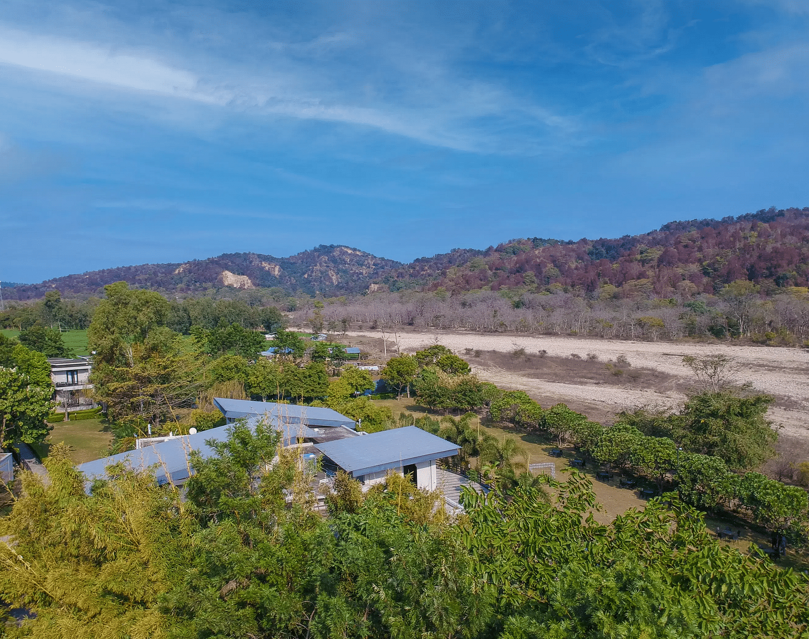 Bird eye view of the Golden Tusk Resort surrounded by lush greenery and a bright beautiful blue sky in the background - Ivory Destinations