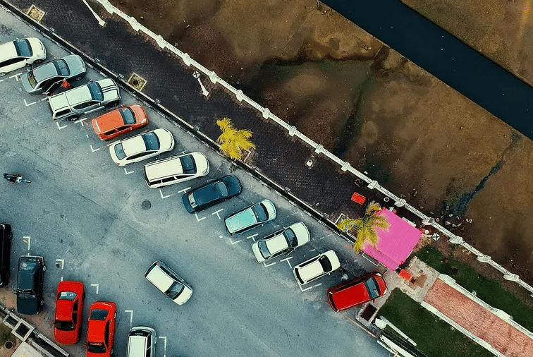 An aerial view of a parking lot with several cars parked in designated spots.