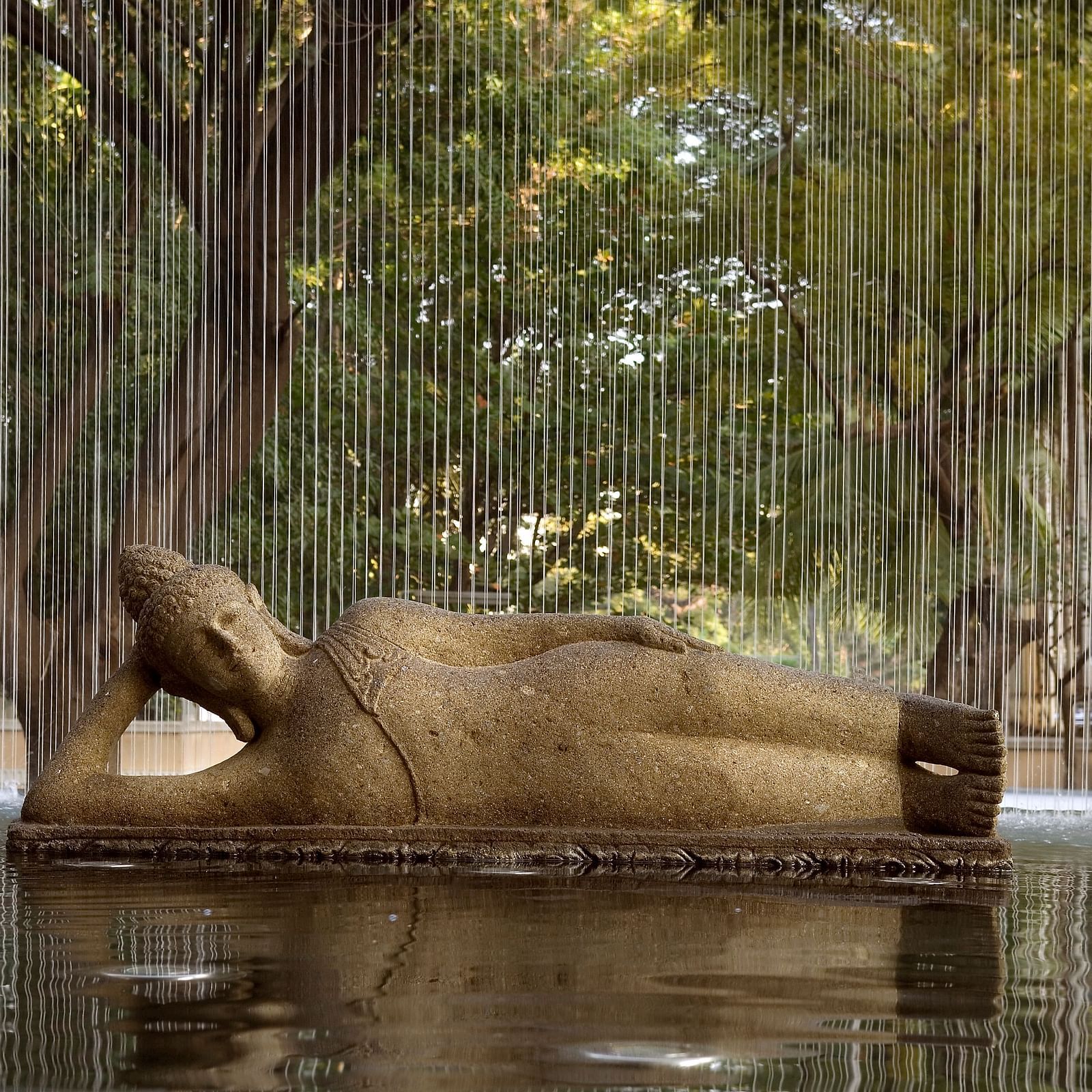 Bronze sculpture of a reclining figure with a water falling in front, creating a unique visual effect - The Raintree, St. Mary's Road.