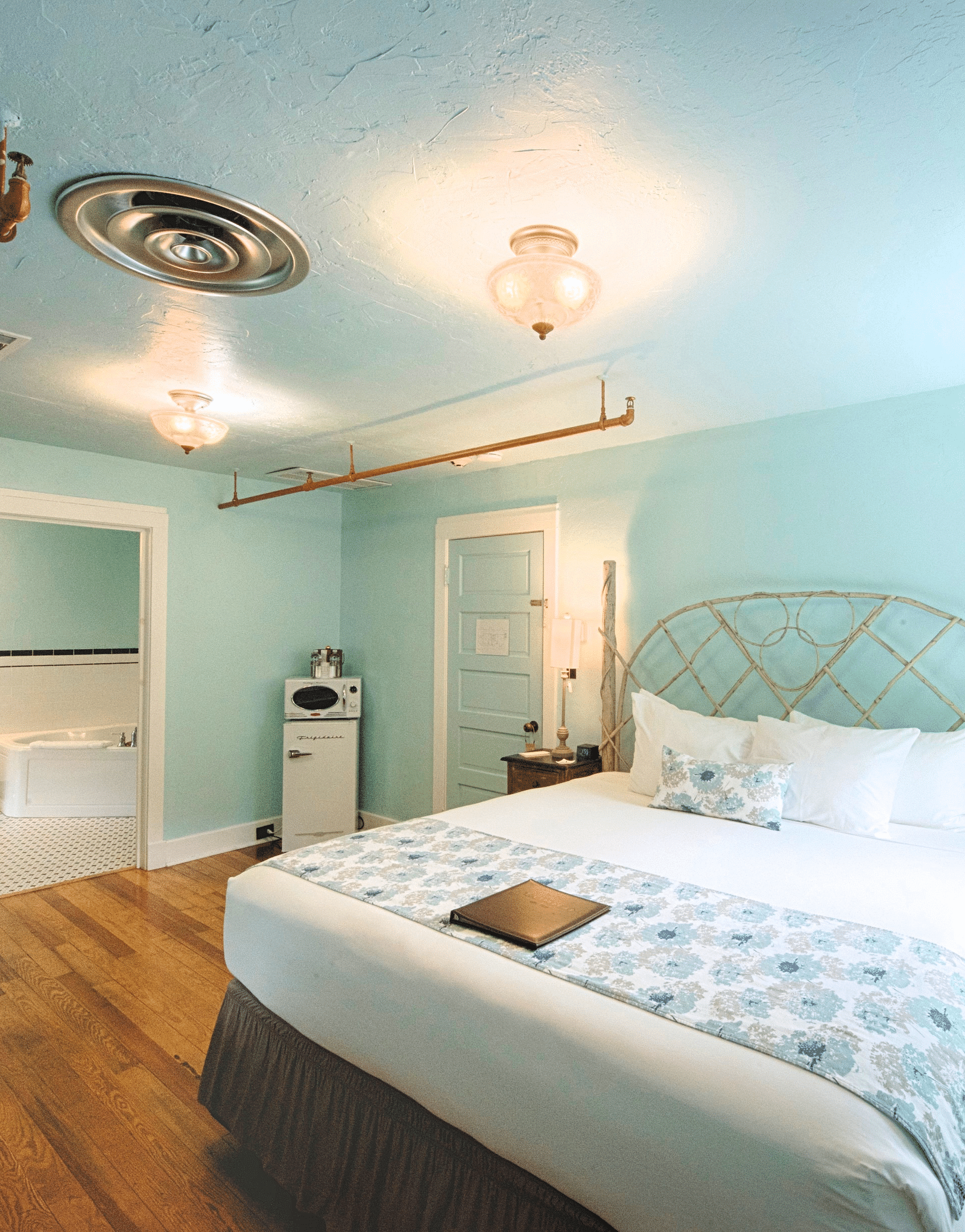 corner view image of the bedroom featuring a comfortable double bed with a window right by the bedside - Historic Tapoco Lodge