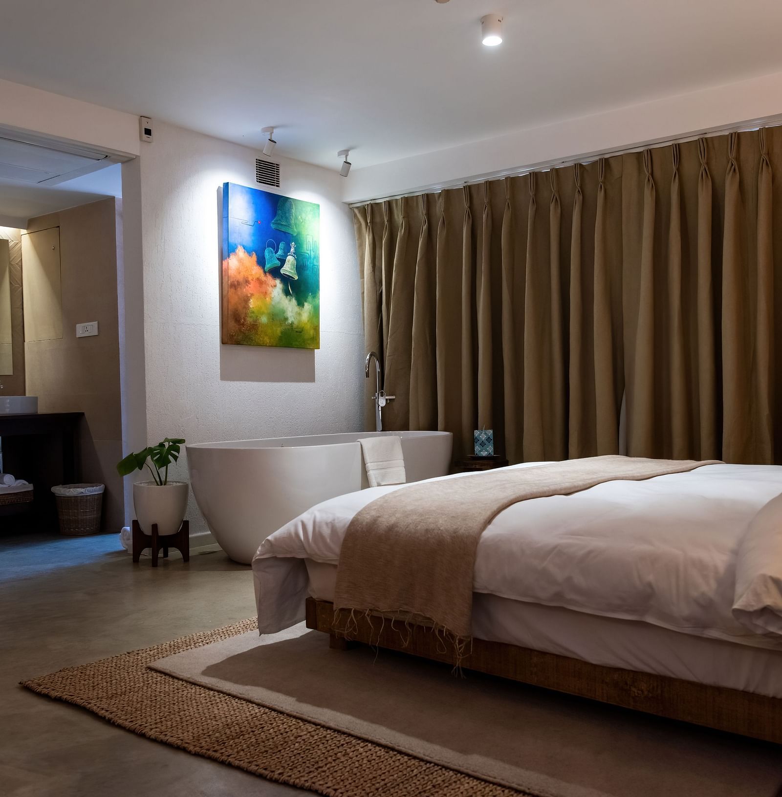 A spacious room with bed, bathtub, wall hanging and the washroom area at the Nepali Suite - The Nanee