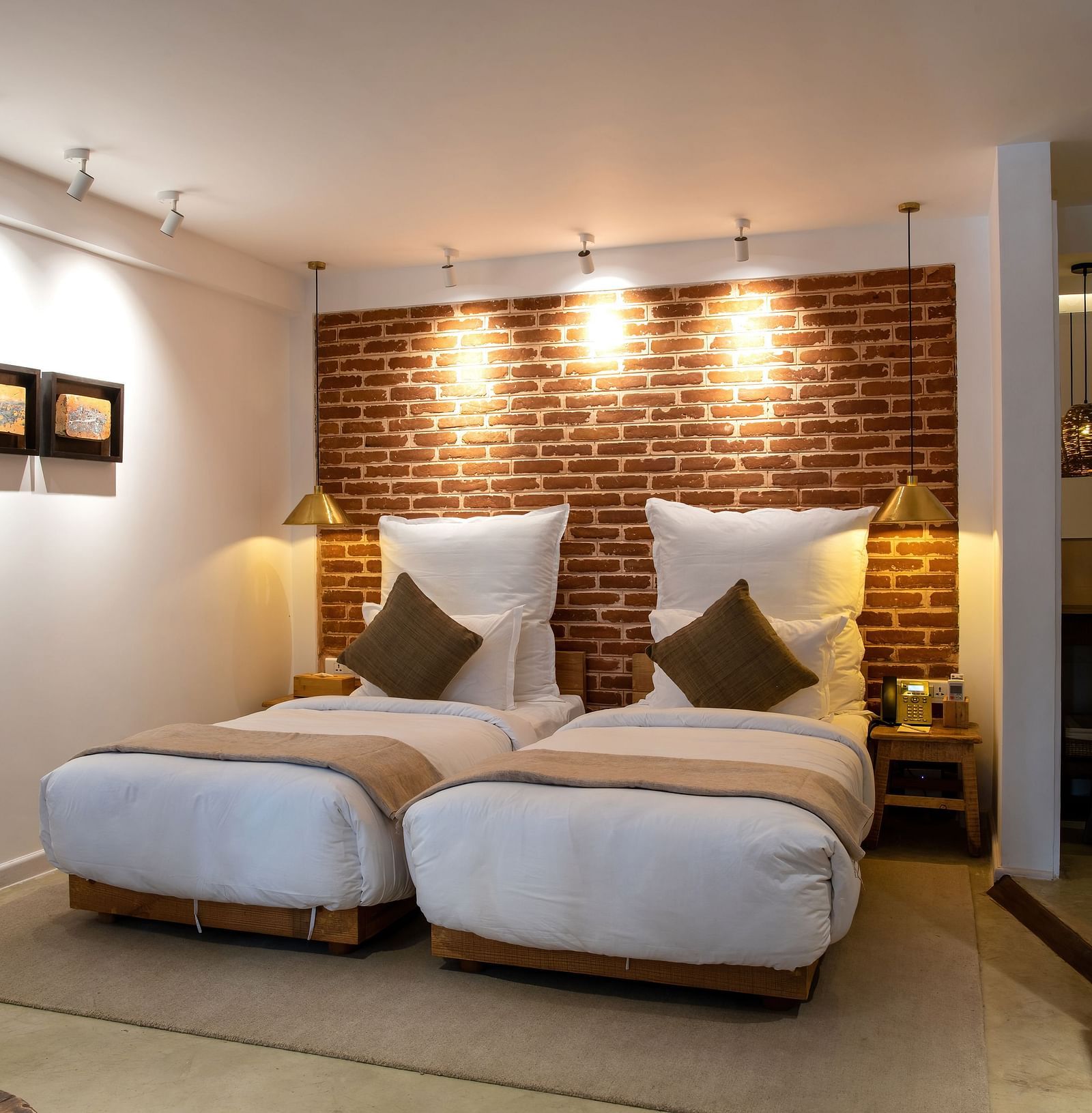 The room at The Nanee includes twin beds, bedside tables with lamps, and three pieces of artwork displayed on the wall.