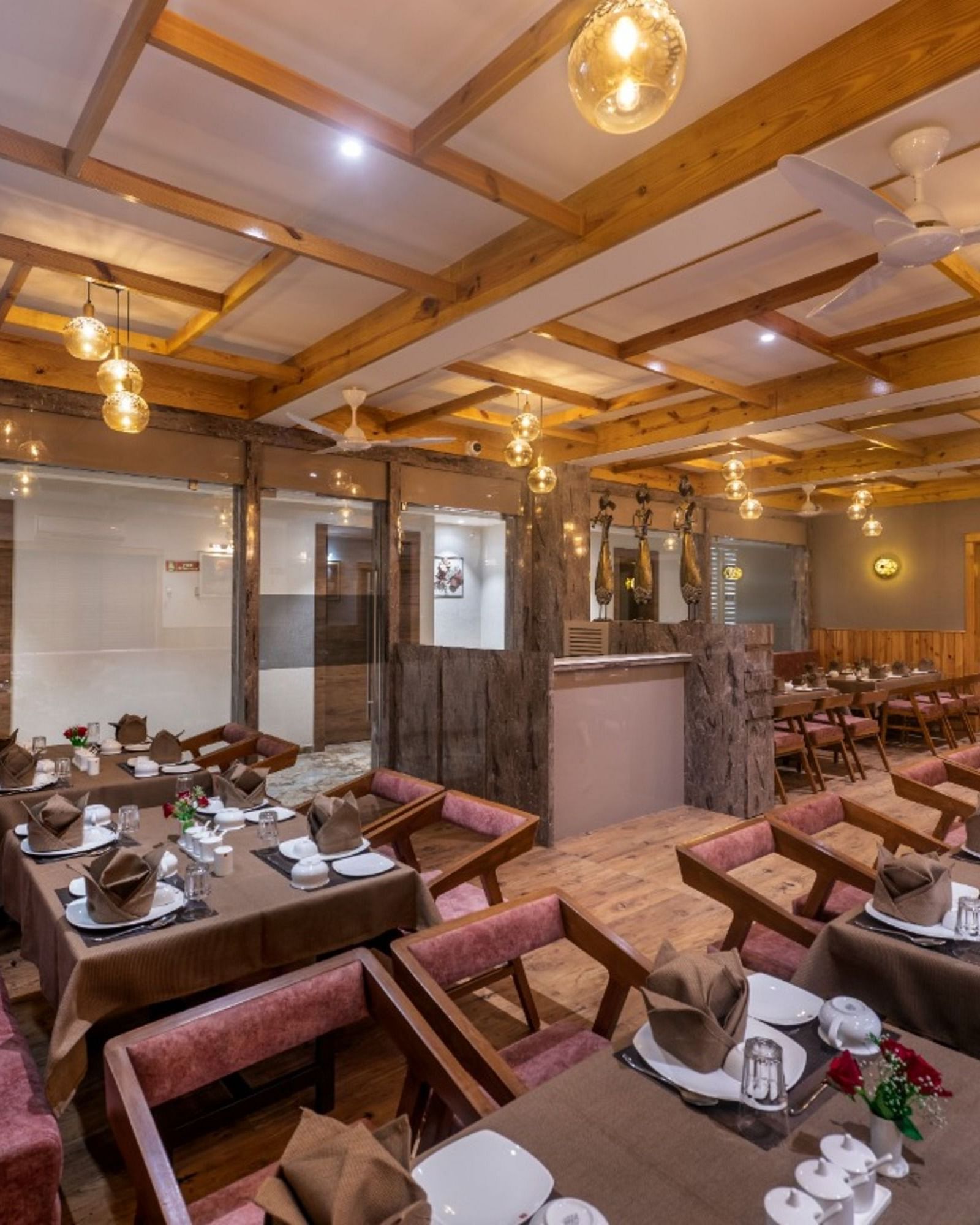 A dining area with multiple tables and chairs set under warm lighting at Angel Lords Eco Inn Amreli.