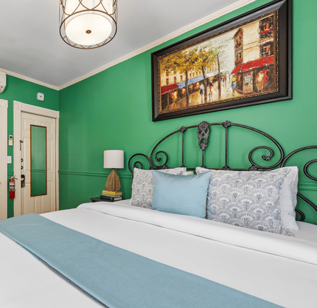 A bedroom with green walls, white bedding, and a decorative iron bed frame at Hartstone Inn
