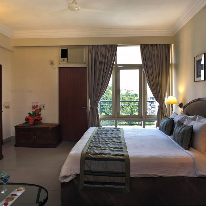 Guests room at The Sonnet, Jamshedpur with a king bed, cupboards, TV and window overlooking greenery.
