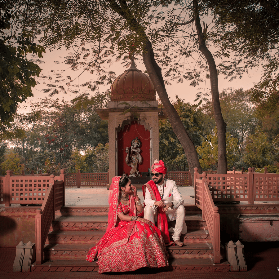 Bride and groom seated in a heritage courtyard during a traditional wedding photoshoot.