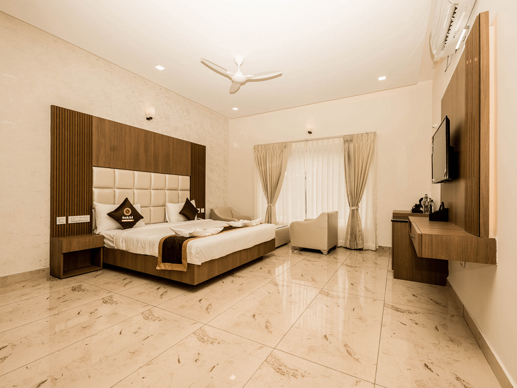 Super Deluxe Room featuring a king size bed, seating area, and a wall-mounted television.- Sukhi - A Luxury Stay Inn, Chikkamagaluru