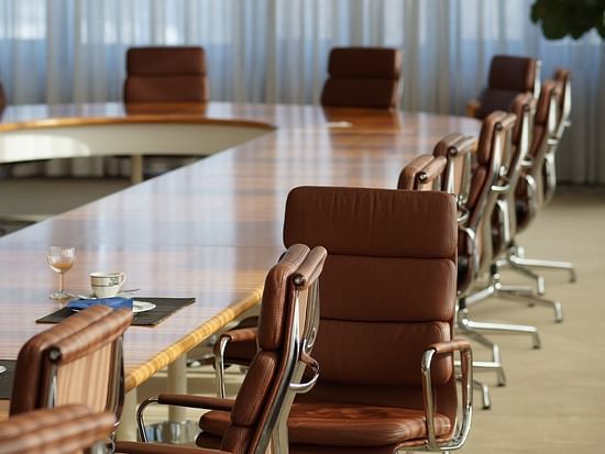A meeting room featuring a u shaped table and brown leather chairs