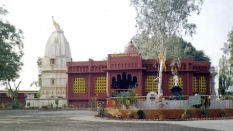 A colourful temple with a large dome in front of a tree.