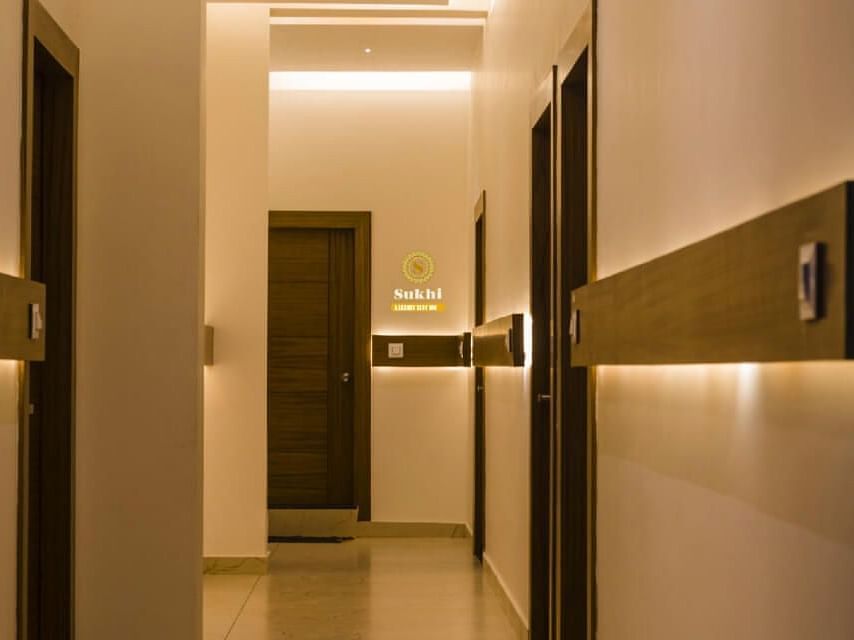 Reception area featuring doors and wall-mounted light fixtures.- Sukhi - A Luxury Stay Inn, Chikkamagaluru