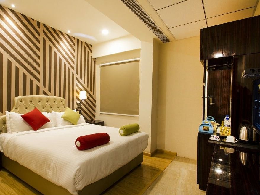 Standard room with bed, television and dressing table at Art Boutique Hotel, Hyderabad