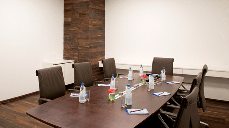 A meeting room at Springs Hotel & Spa, J.C. Road with table, chairs, water bottles, notepads, and wall panel.