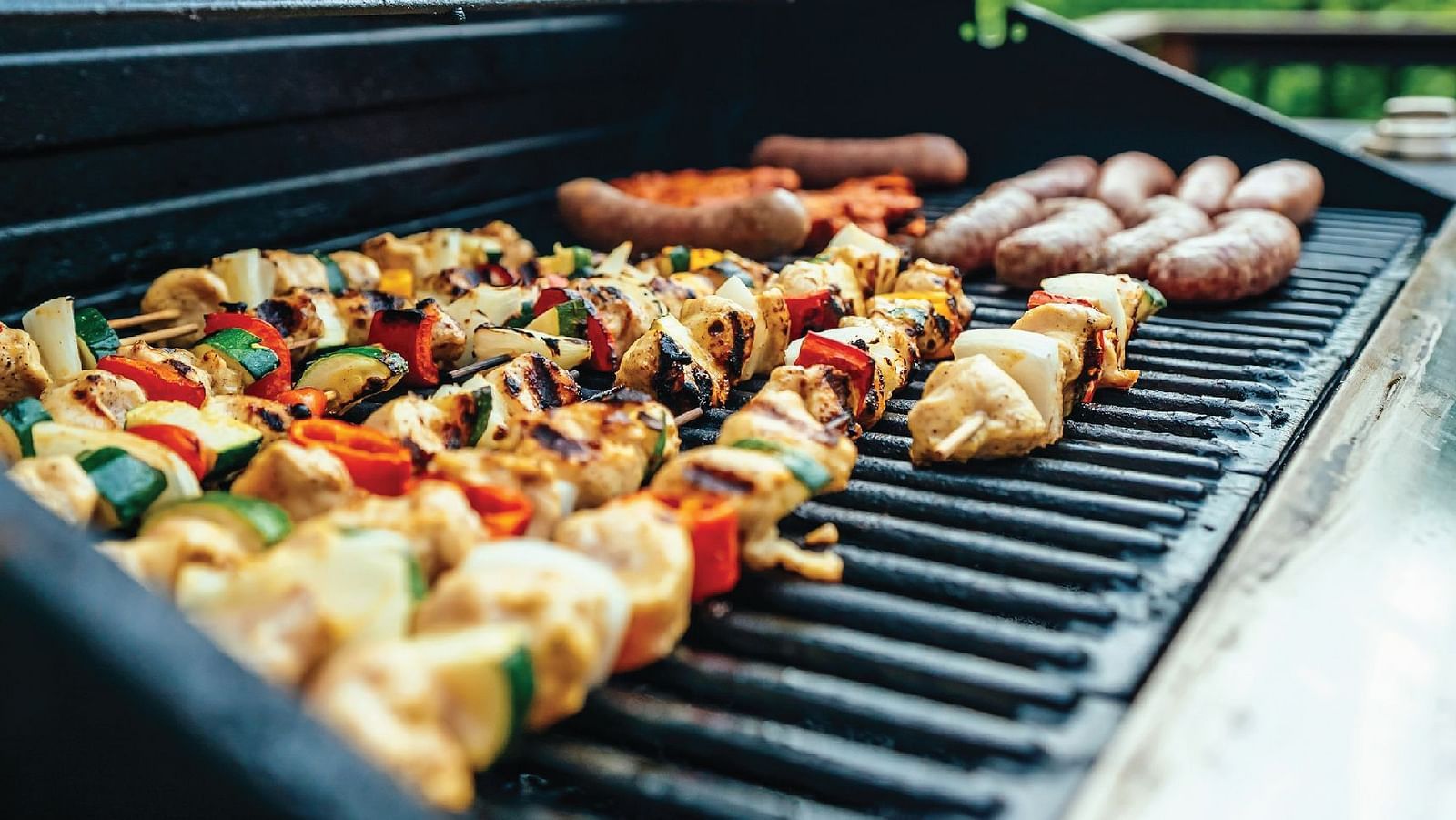 A close up shot of several skewers with seasoned vegetables kept over a barbecue grill.