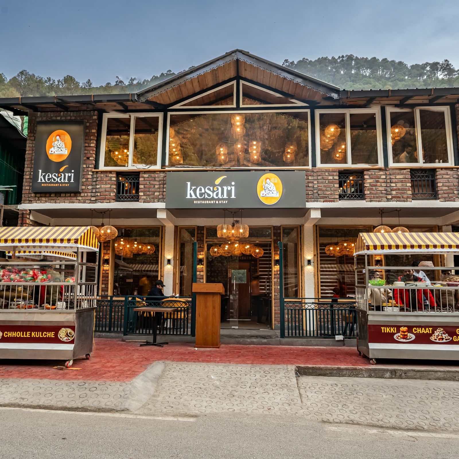 Facade of the Kesari Restaurant with two stalls selling various Indian fast foods with a clear blue sky in the background.