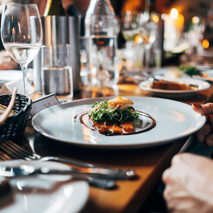 delectable dish on a plate with glasses on a table