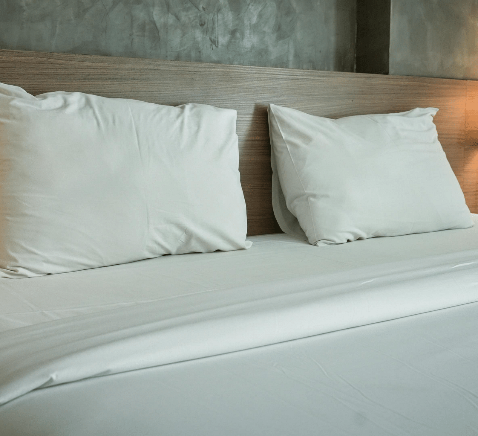 An image of a room with plush bedding, bed side tables and a lamp
