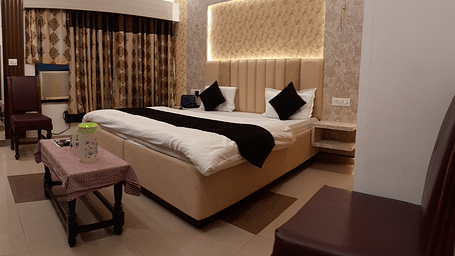 An image showcasing our Executive Rooms in Roorkee with a large king size bed placed in front a wall-mounted television - Motel Divine International, Roorkee