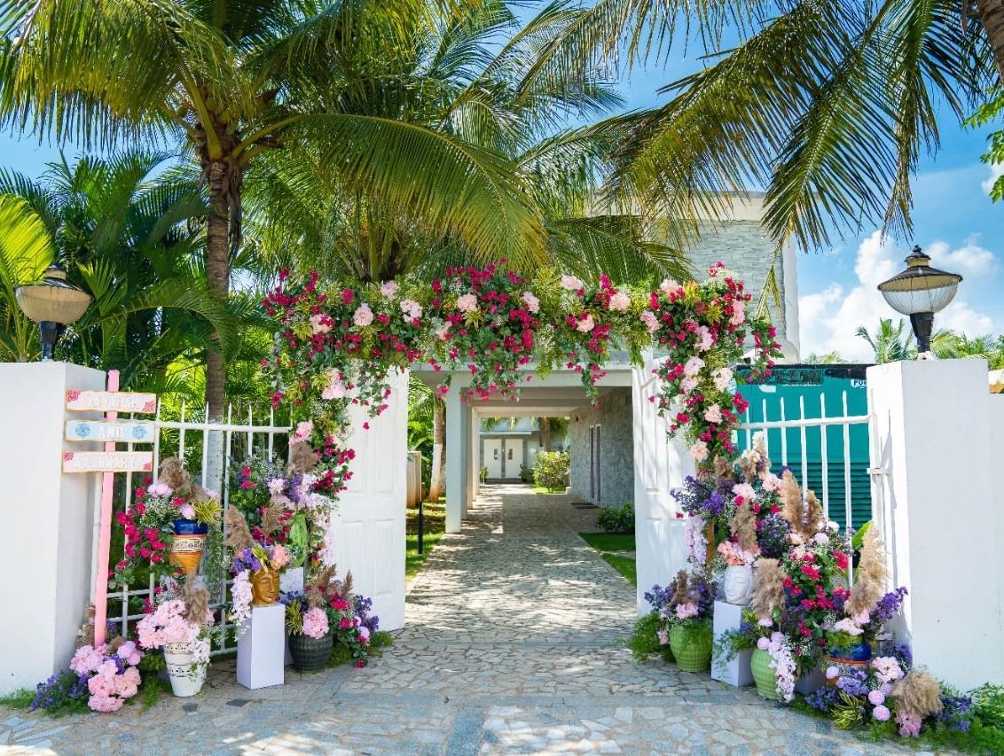An elegant outdoor archway decorated with purple and white flowers, leading into a light-colored building | Grande Pavillion | Grand Bay Resort and Spa