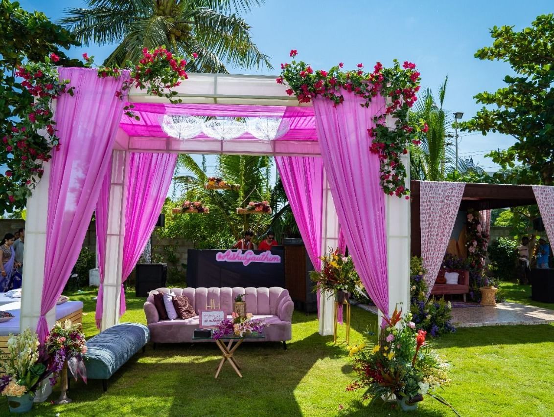 A beautifully decorated outdoor wedding canopy or mandap with pink and white flowers and fabric, set on a green lawn | Grande Pavillion | Grand Bay Resort and Spa