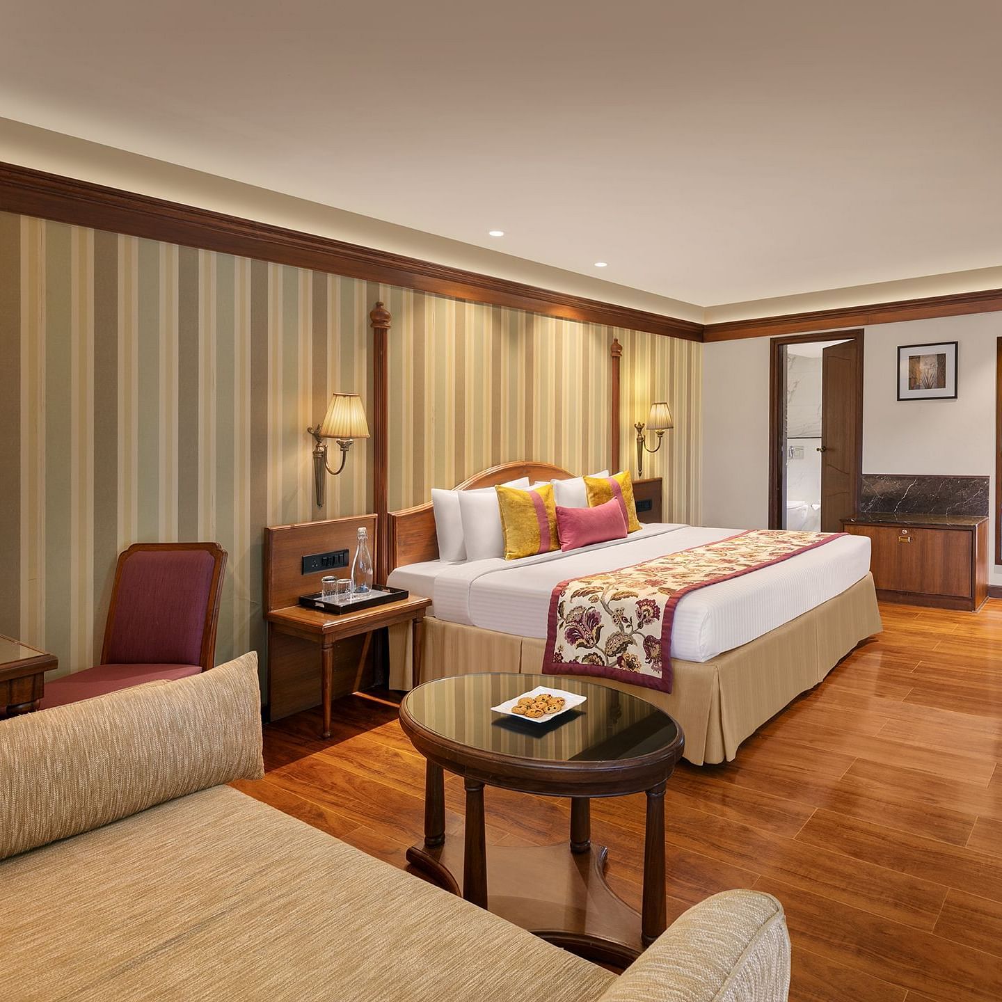 The image shows a luxurious hotel room with a comfortable bed, elegant furniture 
