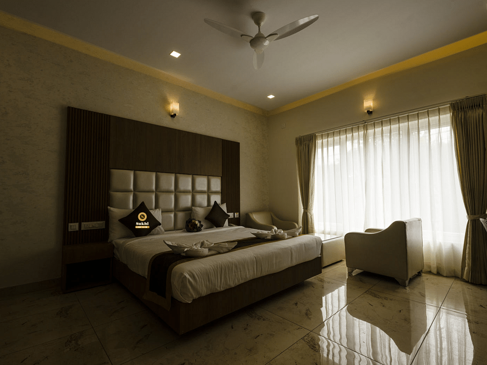 Suite featuring a king size bed, a chair, and sheer curtains. - Sukhi - A Luxury Stay Inn, Chikkamagaluru