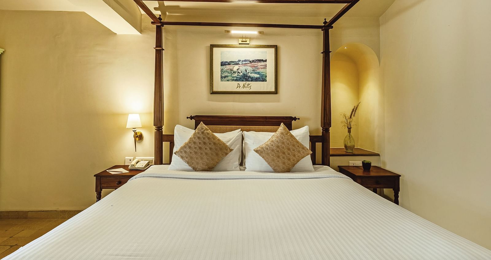 Warmly lit bedroom at Mango Hill Shola, Ooty with a neatly made double bed, side tables, and framed wall art.