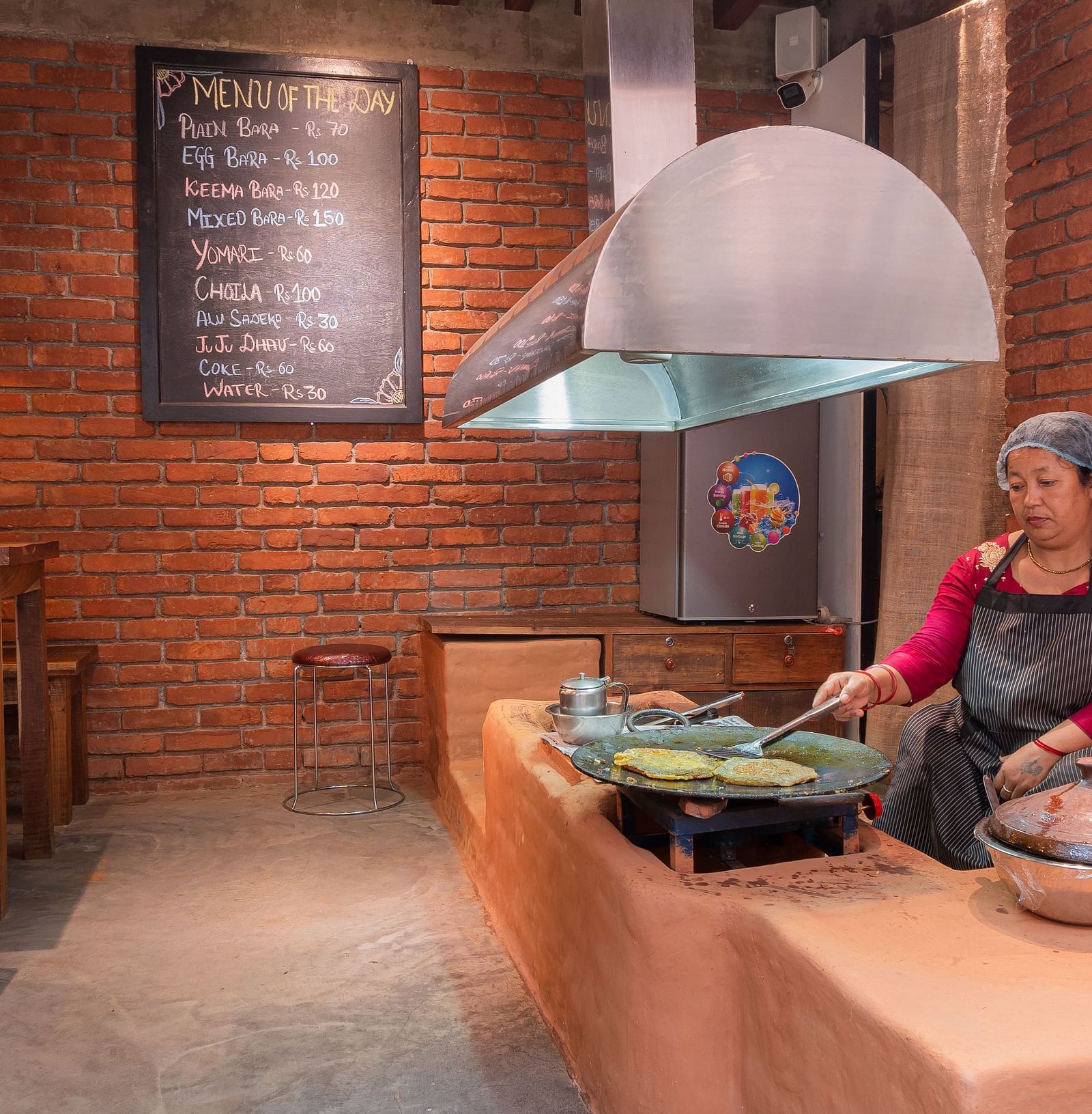 Bara shop at The Nanee where an old women is seen preparing dish on a traditional chulha 
