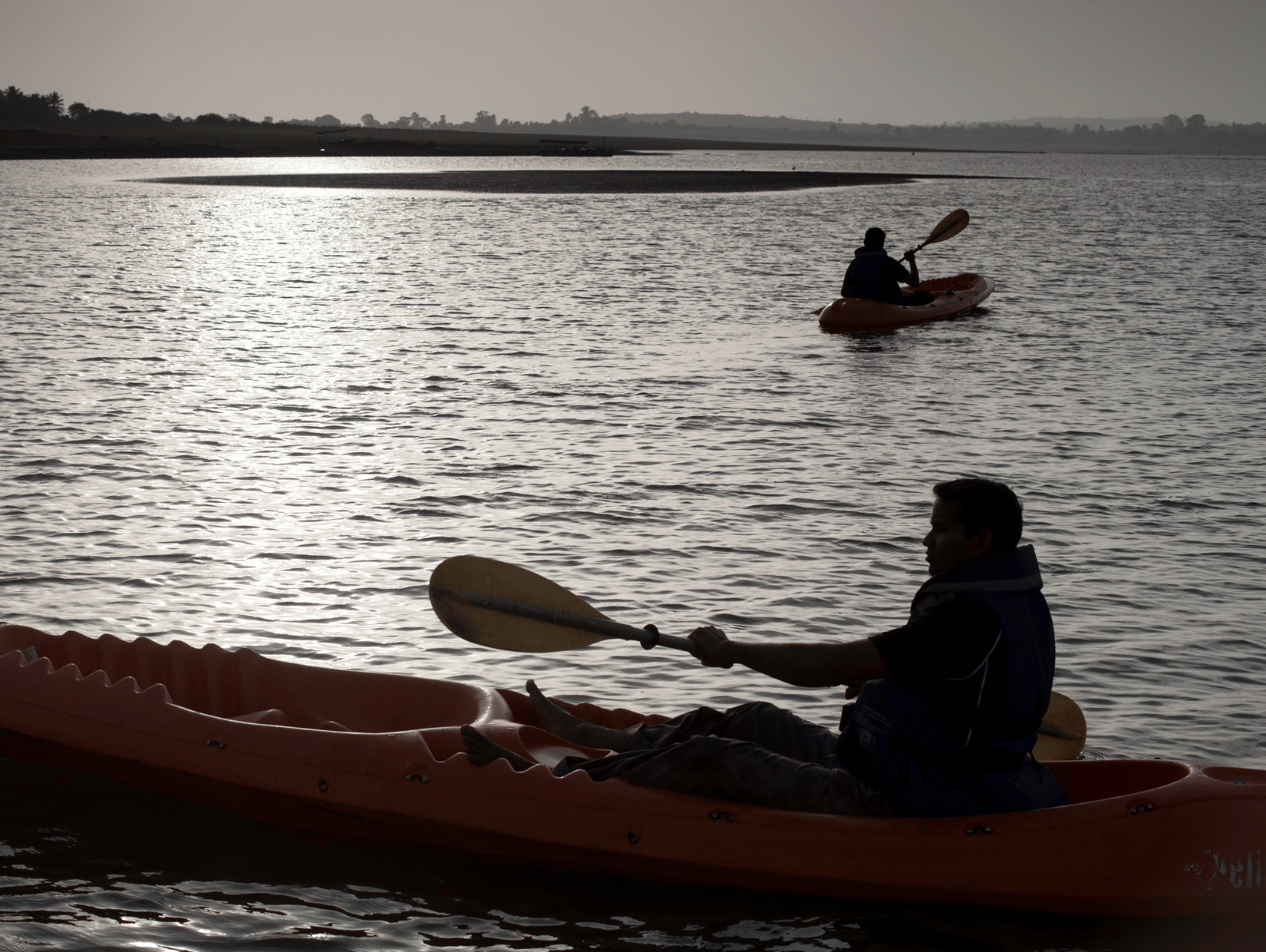 Kayaking In Kabini at The Serai featuring the silhouettes of a couple of people under a sunny sky