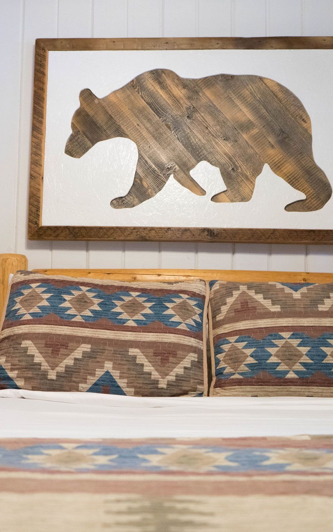 A room with a double bed and an artwork of a bear hung on the wall behind it at Shaver Lake Village Hotel.