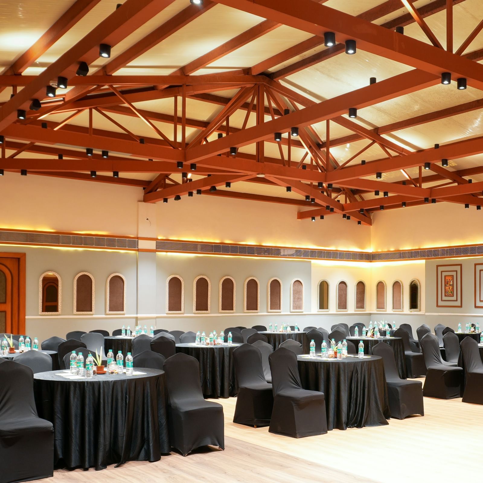 Om I in Vedic Village Spa Resort featuring tables and chairs wrapped in black furniture coverings and modern interiors.. 