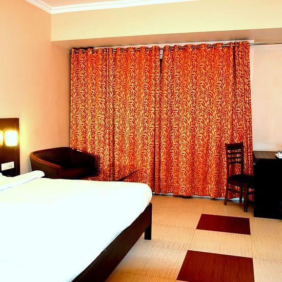 A sideview of Executive Room with bed, TV and a desk | Hotel City Inn, Varanasi