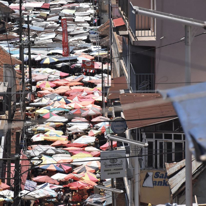 A view from above of the Addis Mercato Market with umbrellas seen on the road having street vendors, next to buildings.