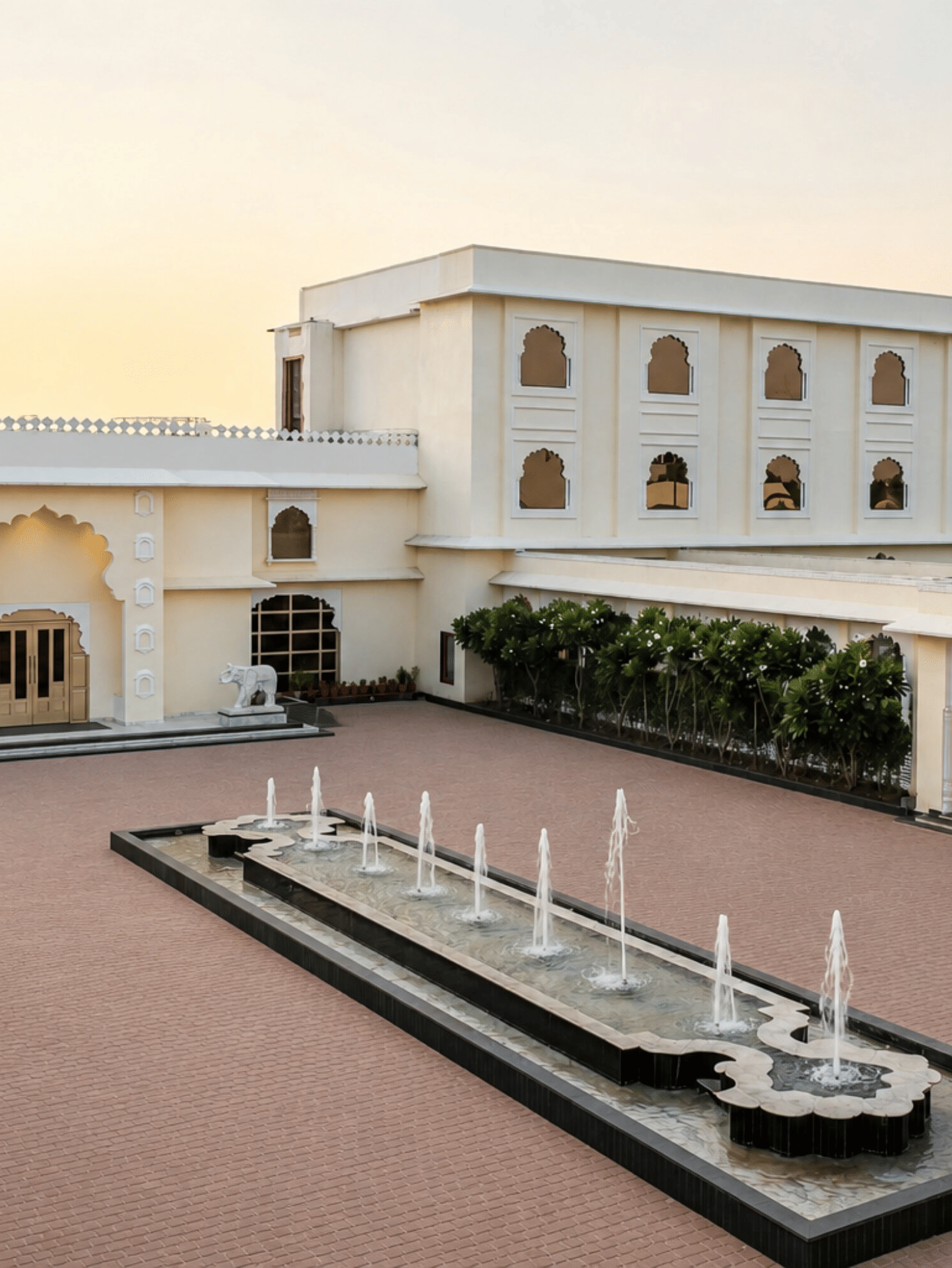 Heritage facade with fountain courtyard at Beelwa Palace, Jaipur at dusk.
