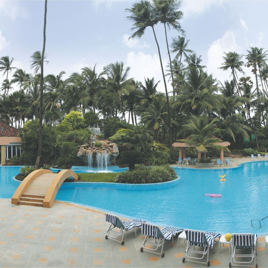 An overview of the Swimming Pool with a bridge and lounge chairs in view at The Retreat Hotel and Convention Centre Madh Island, Mumbai