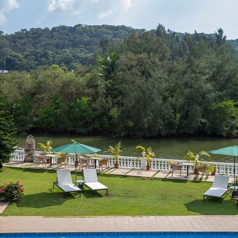 The Riverview outdoor seating arrangement amidst lush green scenery - Stone Wood Riverfront Resort, Siolim