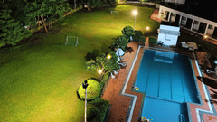 an aerial view of the lawn area next to the swimming pool as seen during the night with goal posts on the lawn and trees covering the surroundings. The lawn area is one of the best wedding venues in Silvassa at VITS Kamats Resort, Silvassa.