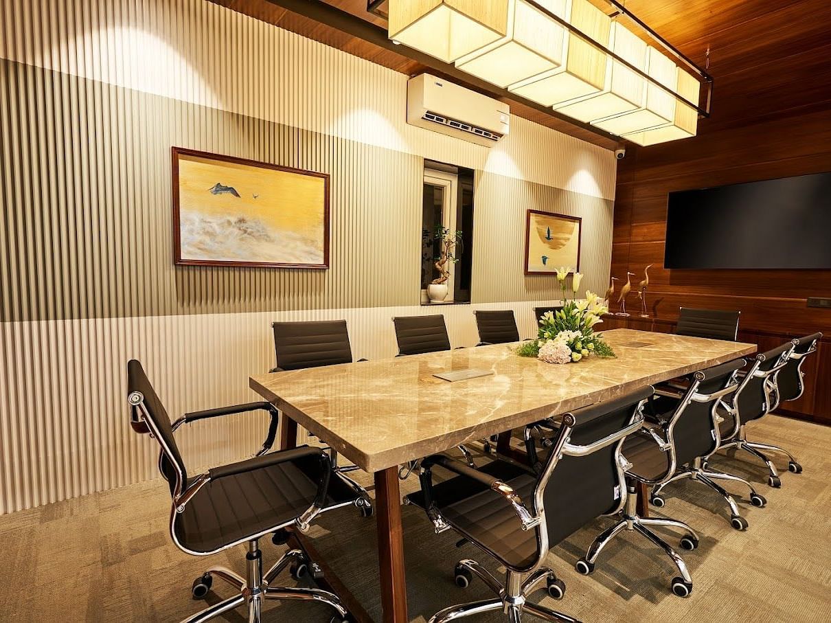 A conference room setting with a centre table and black chairs around it at the boardroom at Visthara - Urban Boutique Hotel