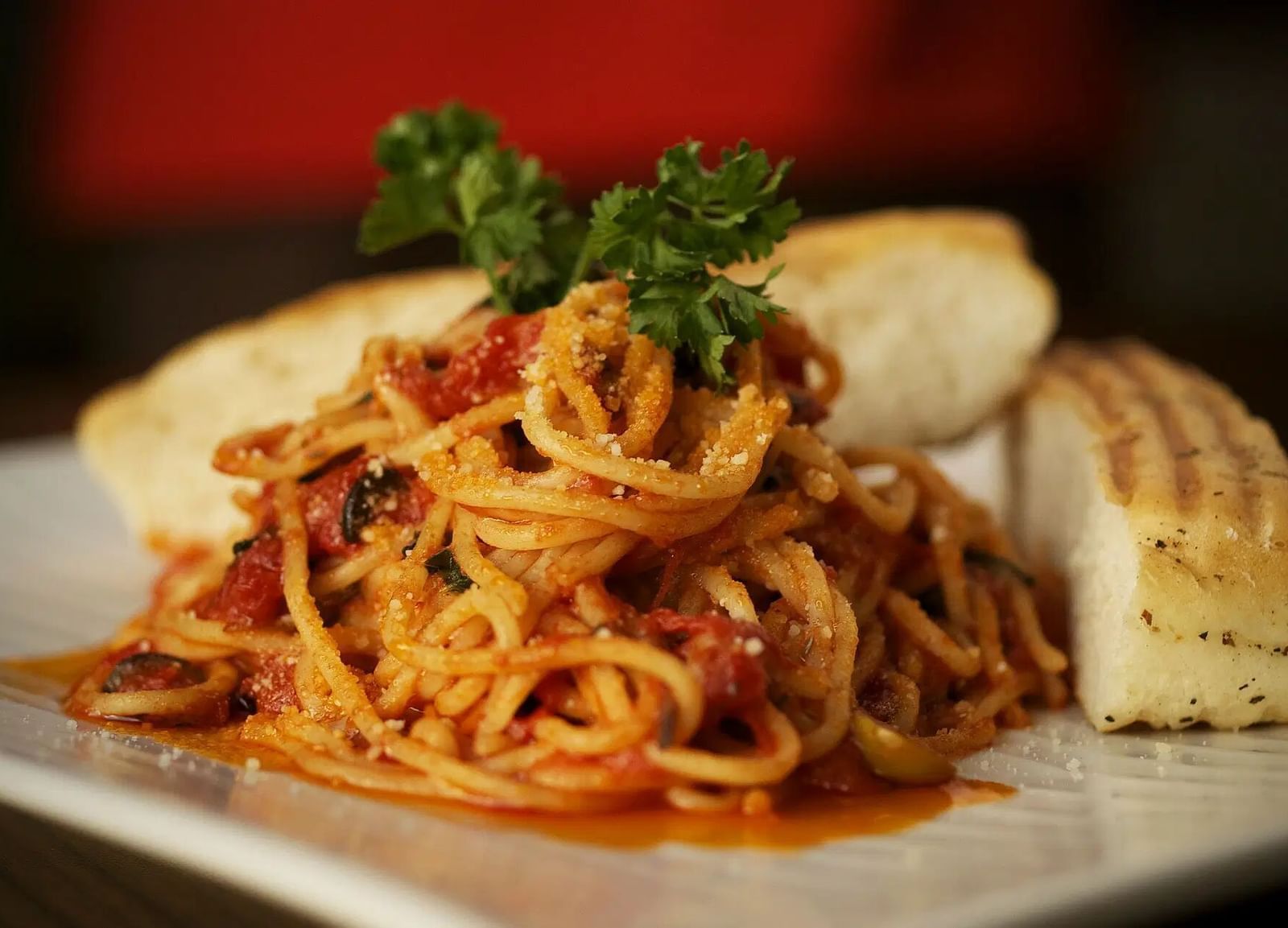 A bowl of pasta with red sauce and bread on a white plate | Altamont Court, Jamaica