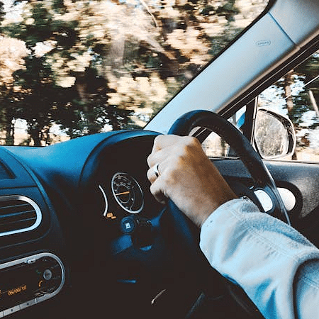 Image of a person driving a car with trees in the background