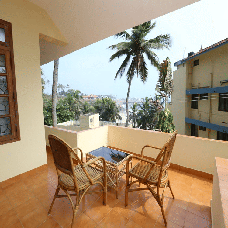 A balcony seating area with chairs and a small table overlooking nearby buildings.