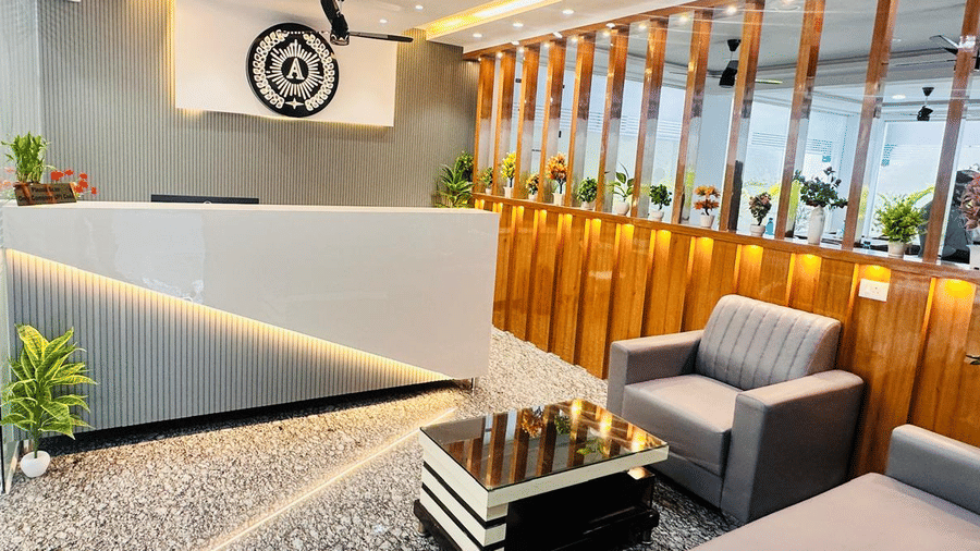 Close-up of a hotel reception desk with a logo on the wall and a seating area | Hotel Aurora Bliss