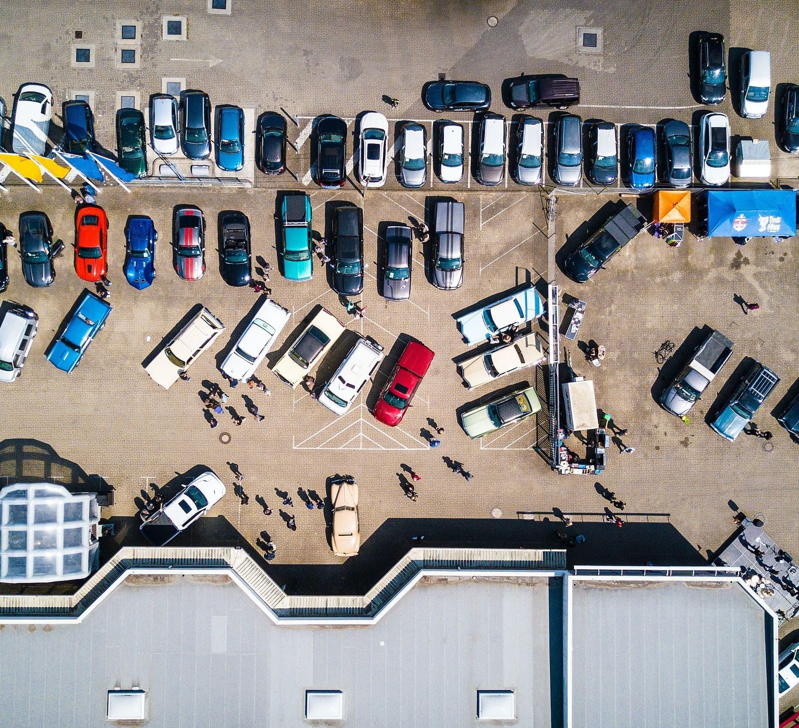 An aerial view of a busy parking lot with various vehicles and people
