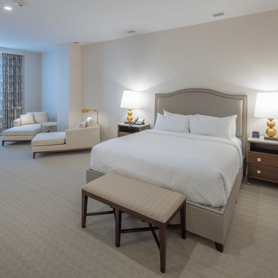 Lakeview King Room featuring a plush bed with two table lamps on its both sides and a sitting space next to the window