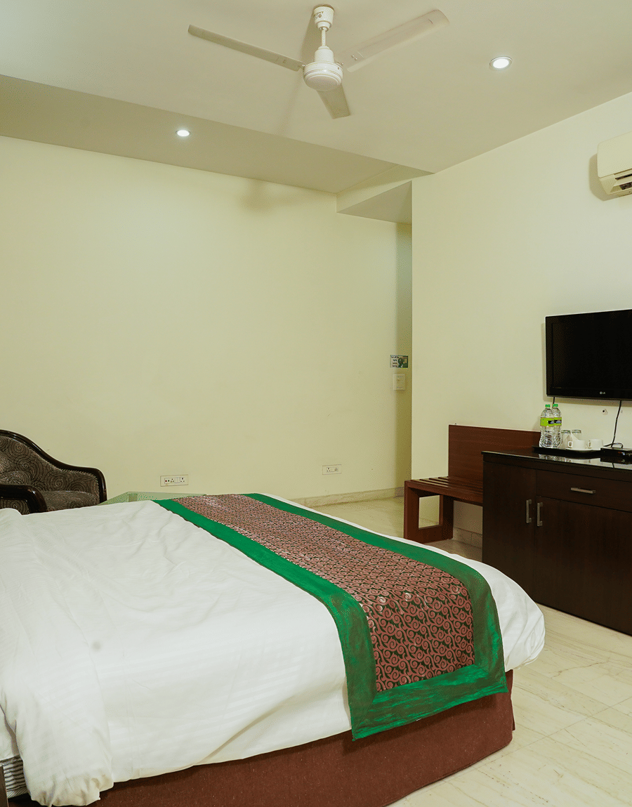 King bed facing a wall-mounted TV and work desk in the Deluxe Room with Balcony at Lime Tree Hotel, IFFCO Chowk
