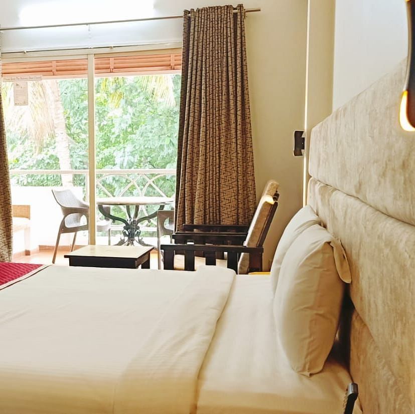 A king size bed in the bedroom attached to a balcony of the Executive Room at Damanganga Valley Resorts
