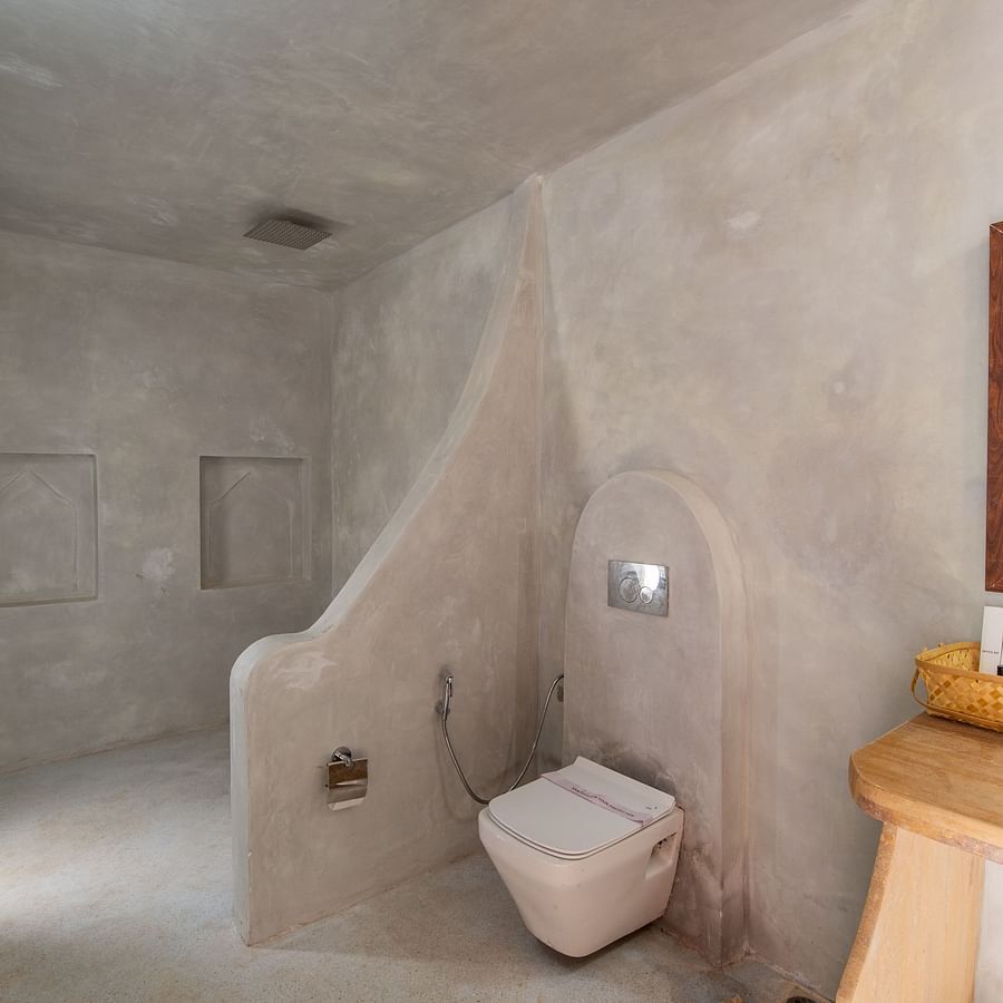 alt-text An image of a western style bathroom with a cabinet, mirror on the wall, a sink, and a commode - Karwaan Jaisalmer 