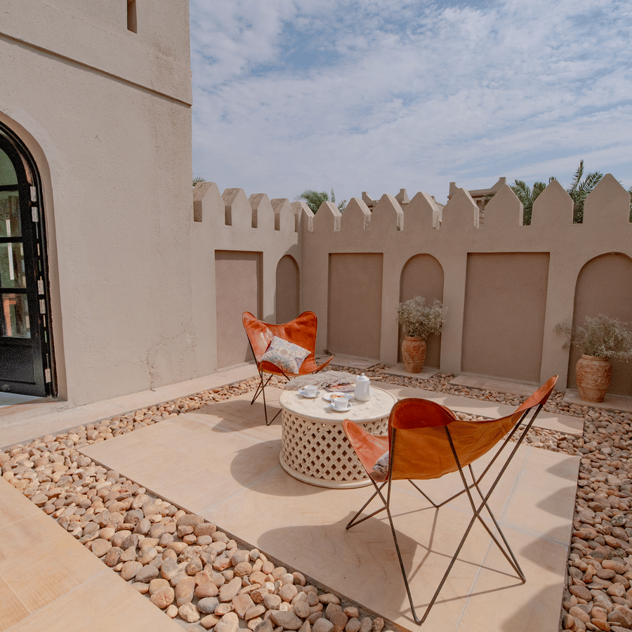 An image of an outdoor sitout area with chairs and centre table where snacks are kept - Karwaan Jaisalmer