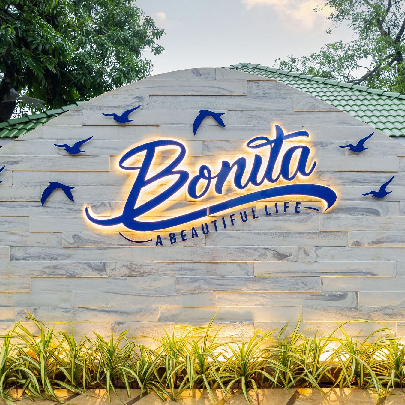 bonita logo - with the text called A baeautiful life in blue illuminated by yellow warm lights and blue birds surrounding the logo.
