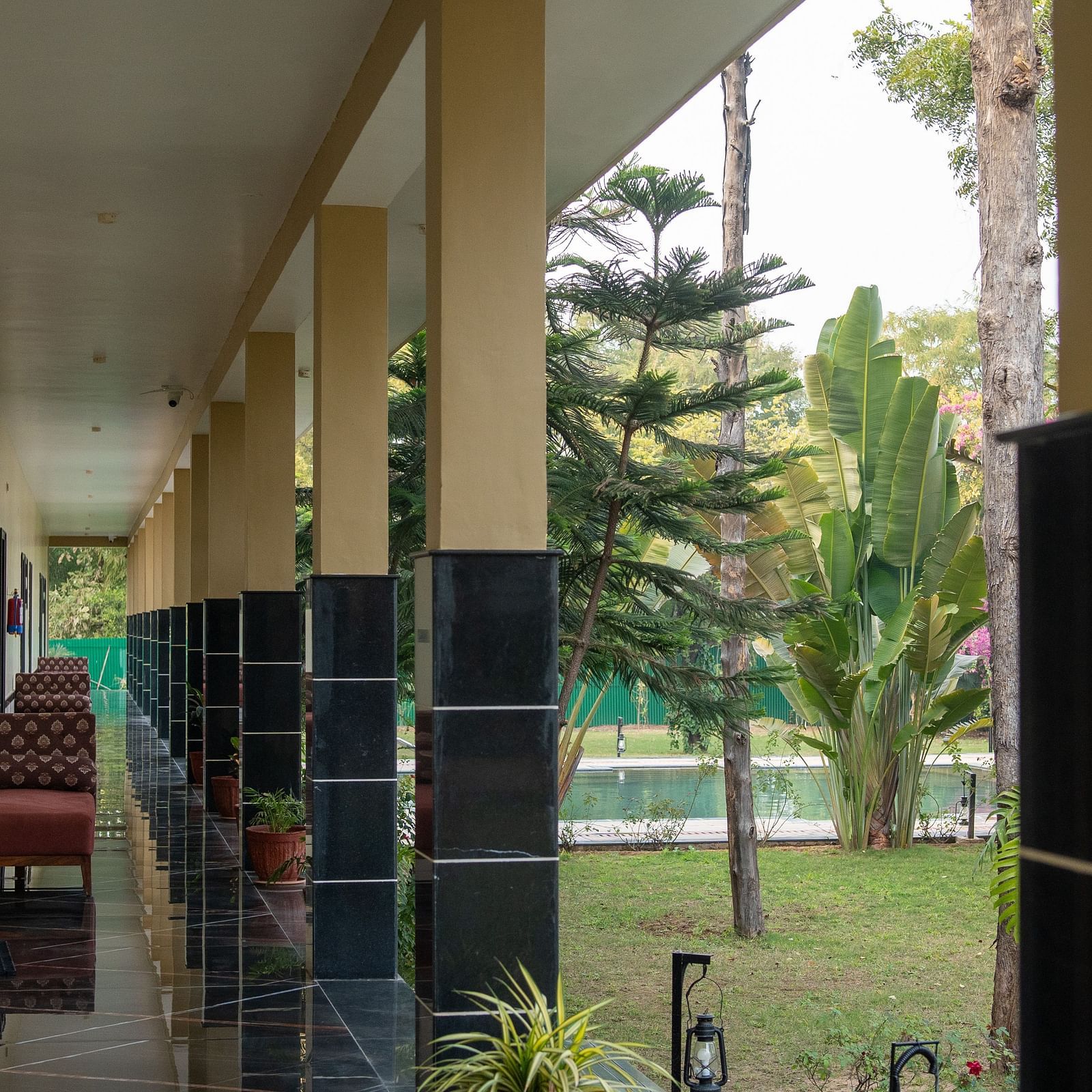 A long verandah area at Aamaghati Jungle Retreat Ranthambore with pillars and views of the garden.